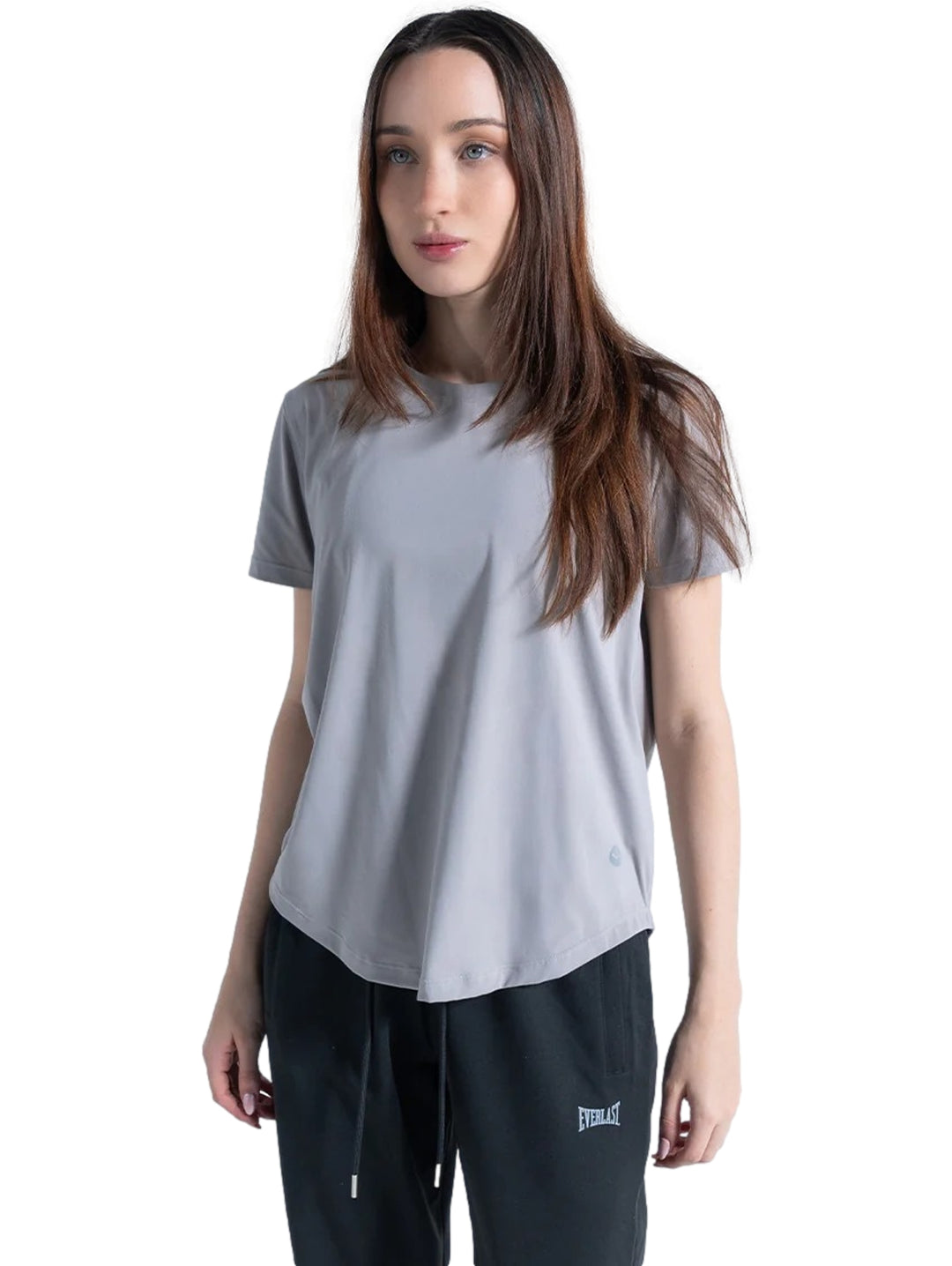 Mujer vistiendo una playera deportiva de color gris neutro de manga corta y cuello redondo.