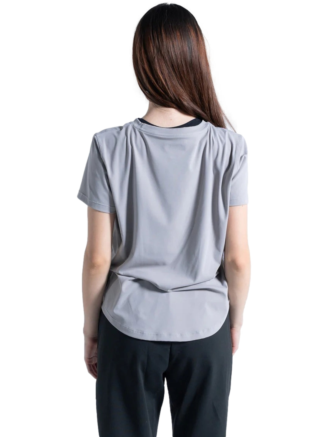 Mujer vistiendo una playera deportiva de color gris neutro de manga corta y cuello redondo.