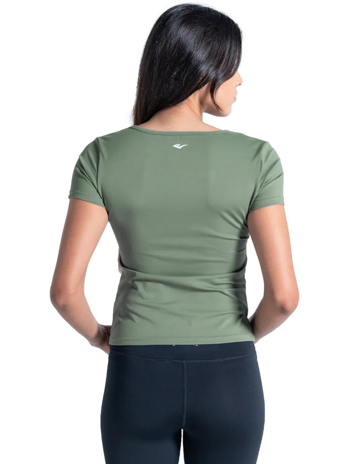 Mujer vistiendo playera deportiva color verde con cuello drapeado y manga corta.