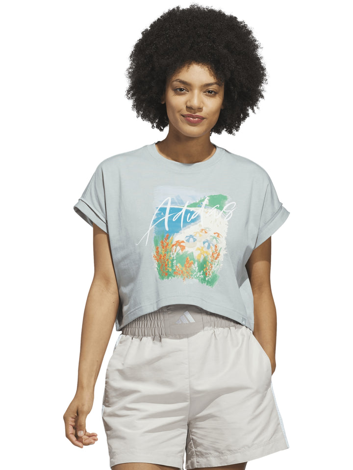 Playera Adidas color Wonder Sage con estampado gráfico frontal y cuello redondo.