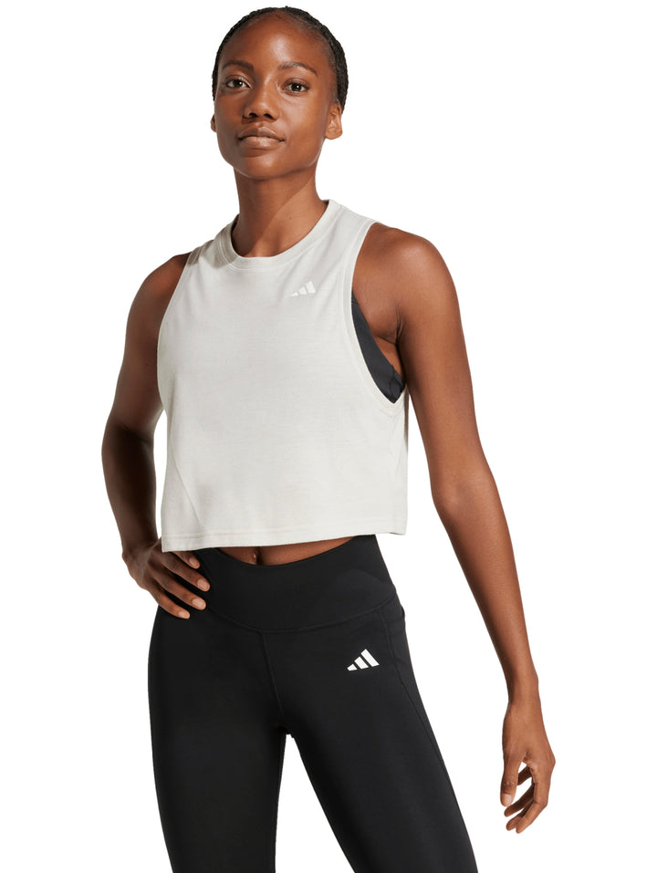 Mujer vistiendo una camiseta deportiva sin mangas de color crema marca Adidas con corte boxy.