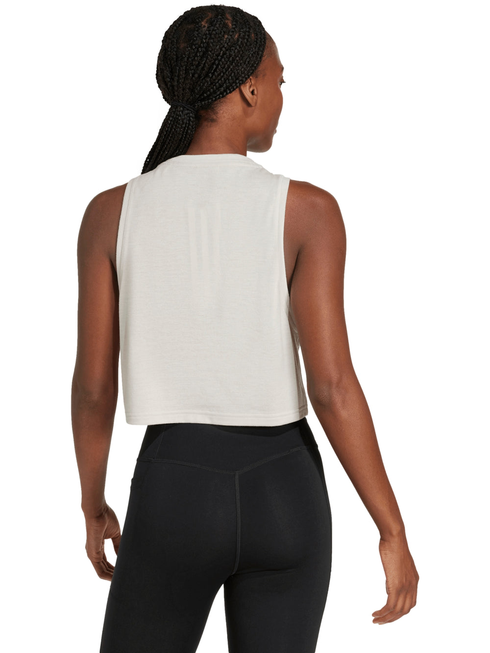 Mujer vistiendo una camiseta deportiva sin mangas de color crema marca Adidas con corte boxy.