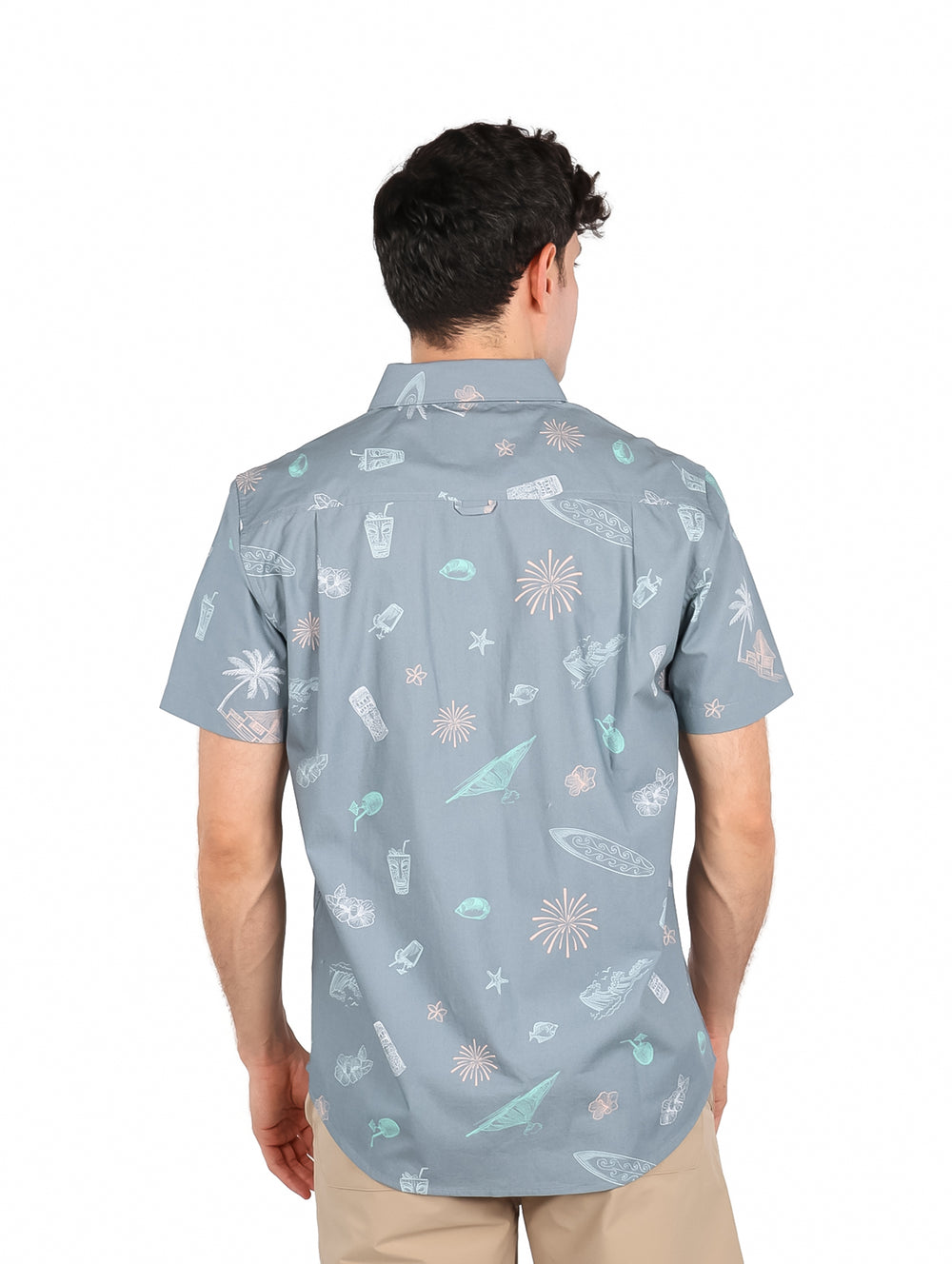 Hombre vistiendo camisa de manga corta color gris con estampado tropical de surf.