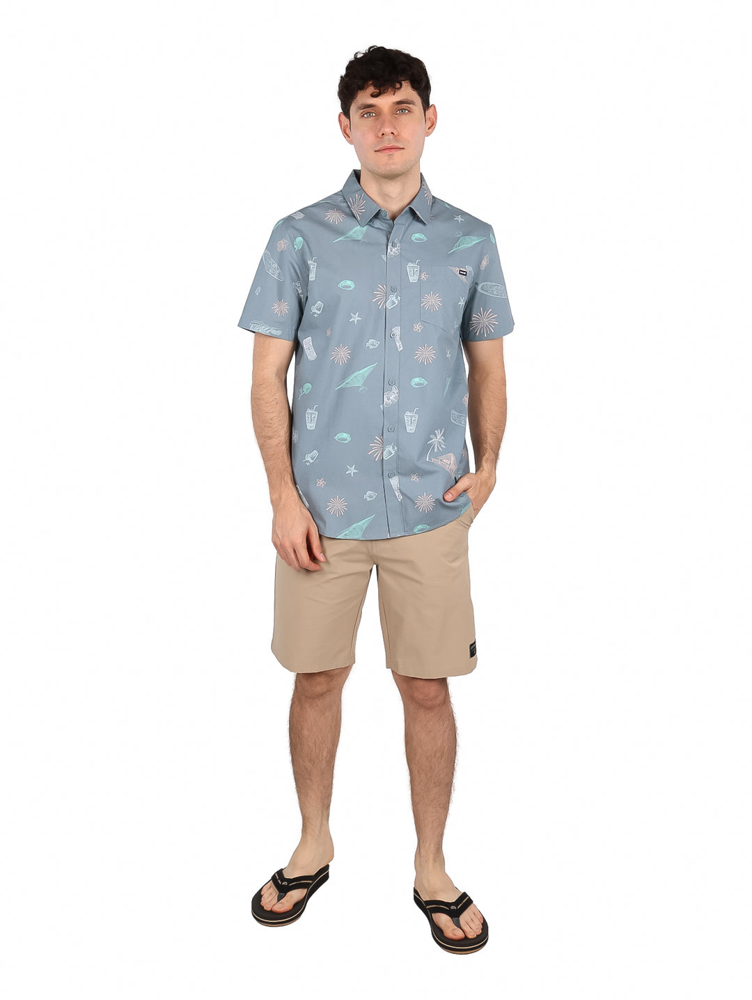 Hombre vistiendo camisa de manga corta color gris con estampado tropical de surf.