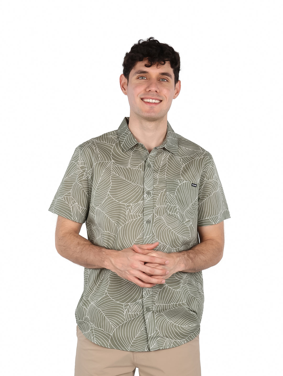 Hombre vistiendo una camisa de manga corta color verde con estampado de hojas blancas.