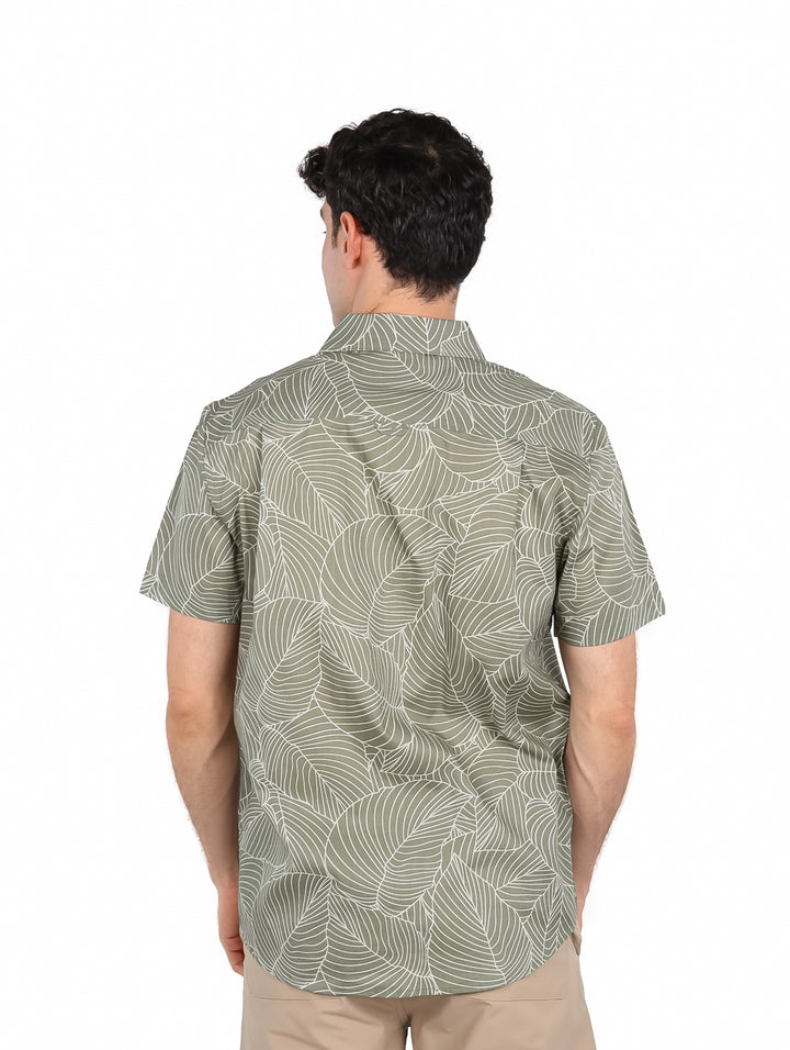 Hombre vistiendo una camisa de manga corta color verde con estampado de hojas blancas.