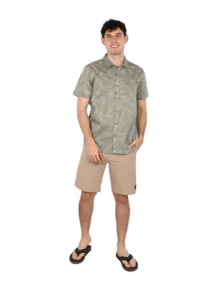 Hombre vistiendo una camisa de manga corta color verde con estampado de hojas blancas.