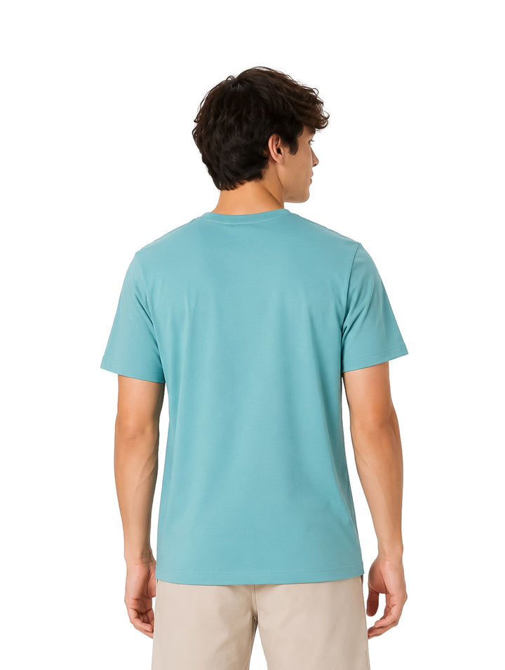 Hombre usando playera Hurley color Broken Jade con bolsillo frontal y pantalones beige.