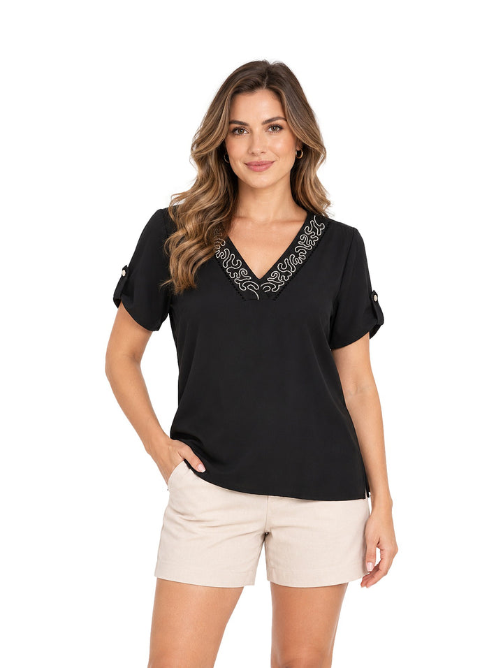 Mujer vistiendo blusa negra de marca Gavini con bordado blanco en el cuello en V y mangas cortas.