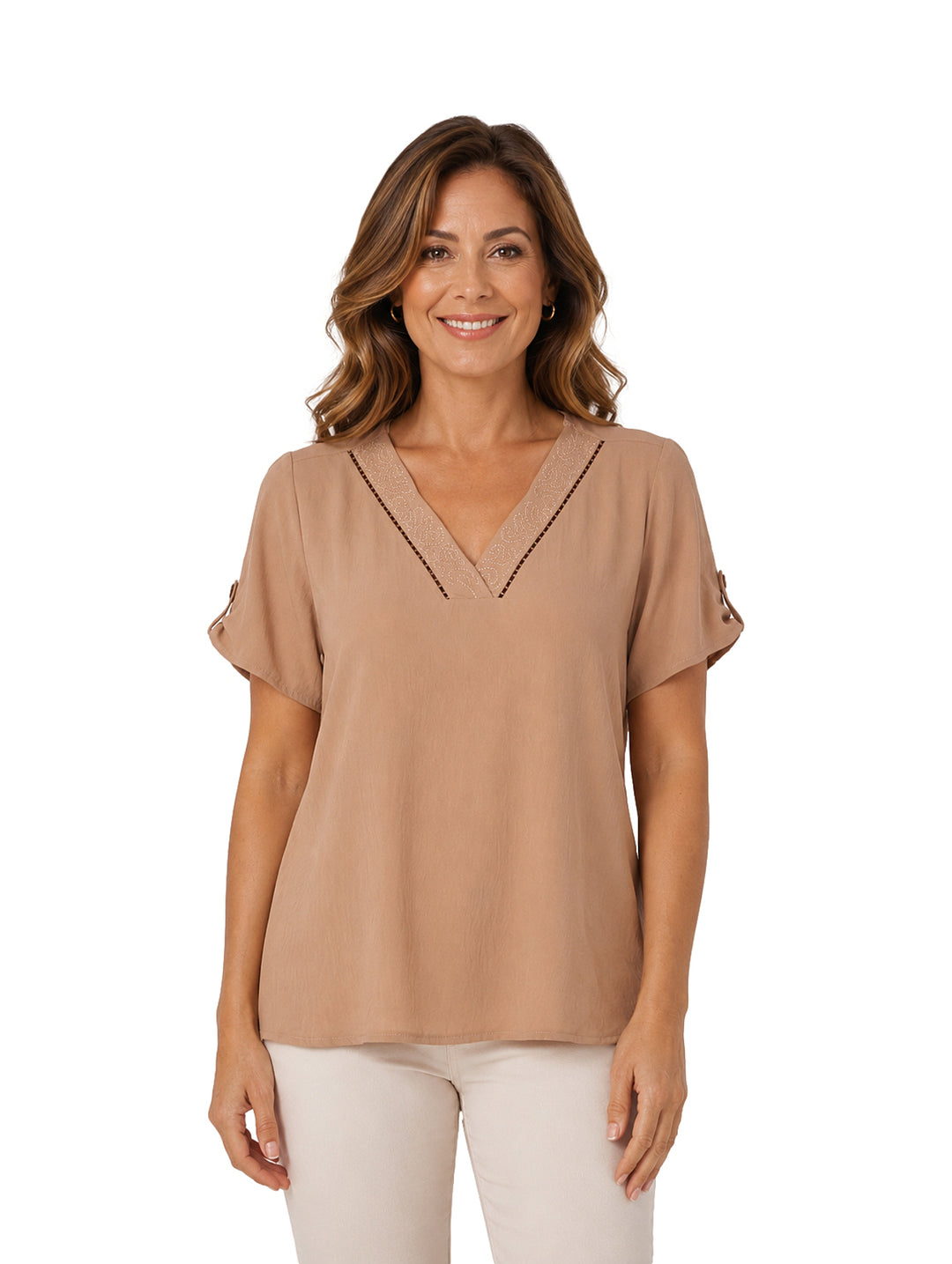 Mujer vistiendo una blusa color beige con cuello en V y detalles decorativos en marrón.