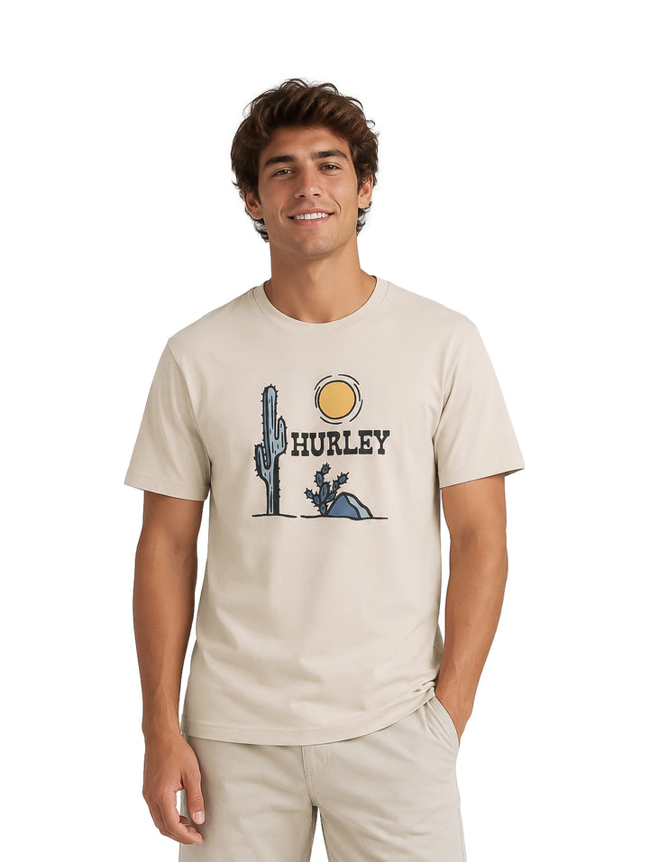 Hombre vistiendo playera color bone de marca Hurley con estampado de cactus y sol en el pecho.