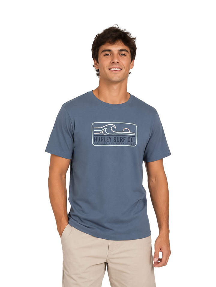 Hombre vistiendo playera Hurley color azul hipnótico con logo blanco en el pecho.