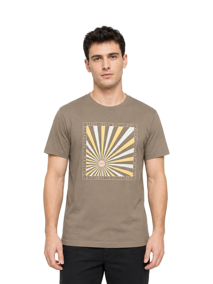 Hombre vistiendo playera Hurley color iguana con estampado gráfico frontal en tonos beige y blanco.