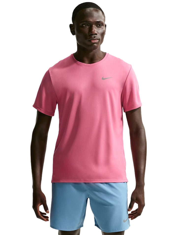 Hombre vistiendo camiseta deportiva Nike color rosa y shorts azules.