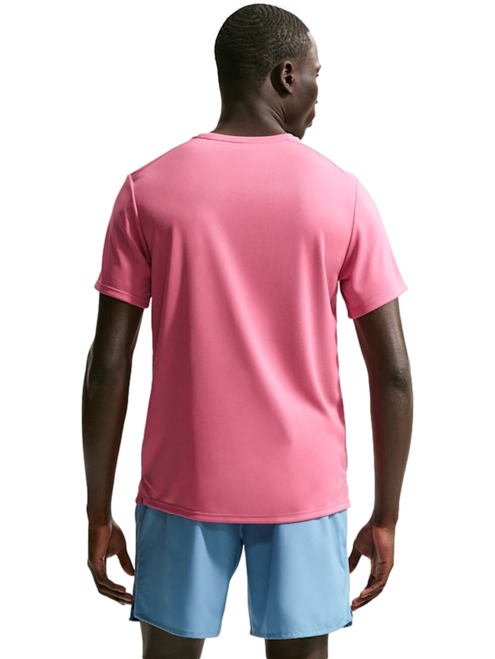 Hombre vistiendo camiseta deportiva Nike color rosa y shorts azules.