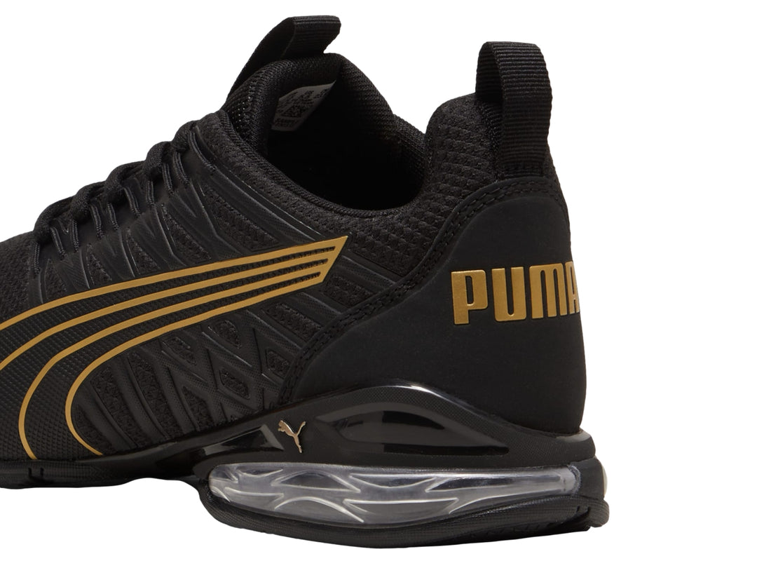 Tenis deportivos PUMA color negro con rayas en oro rosa y cámara de aire en el talón.