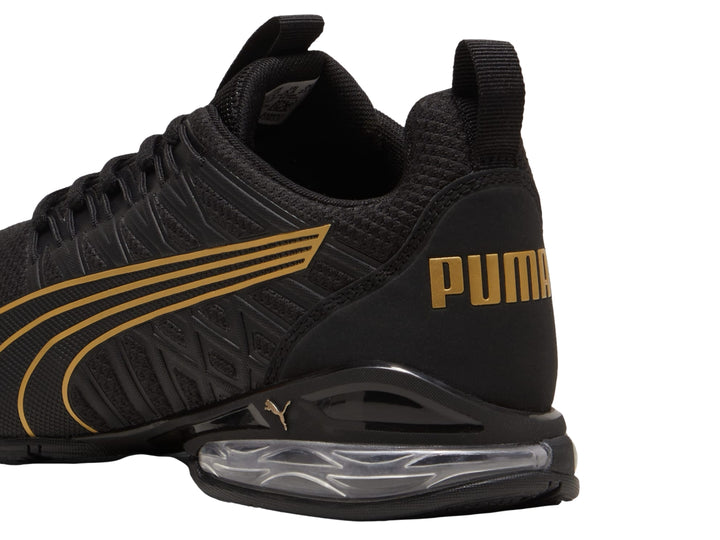 Tenis deportivos PUMA color negro con rayas en oro rosa y cámara de aire en el talón.