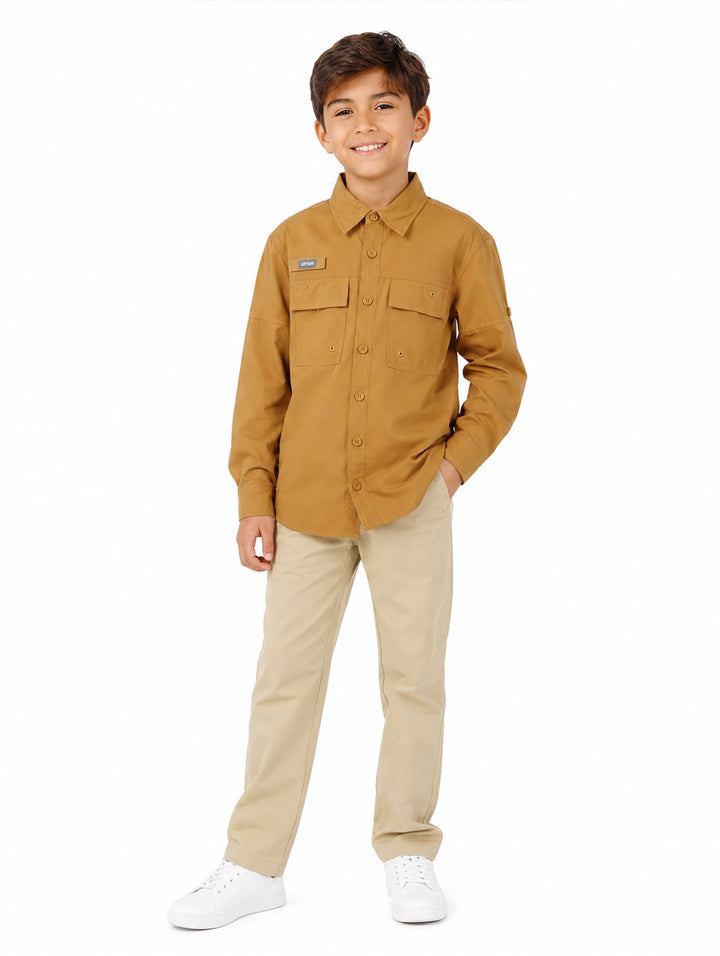 Niño vistiendo una camisa de manga larga color delta con dos bolsillos frontales y cuello