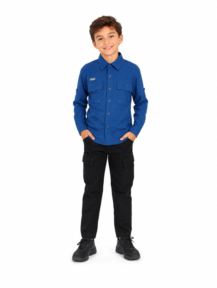 Nino vistiendo una camisa azul de manga larga estilo outdoor con bolsillos frontales.