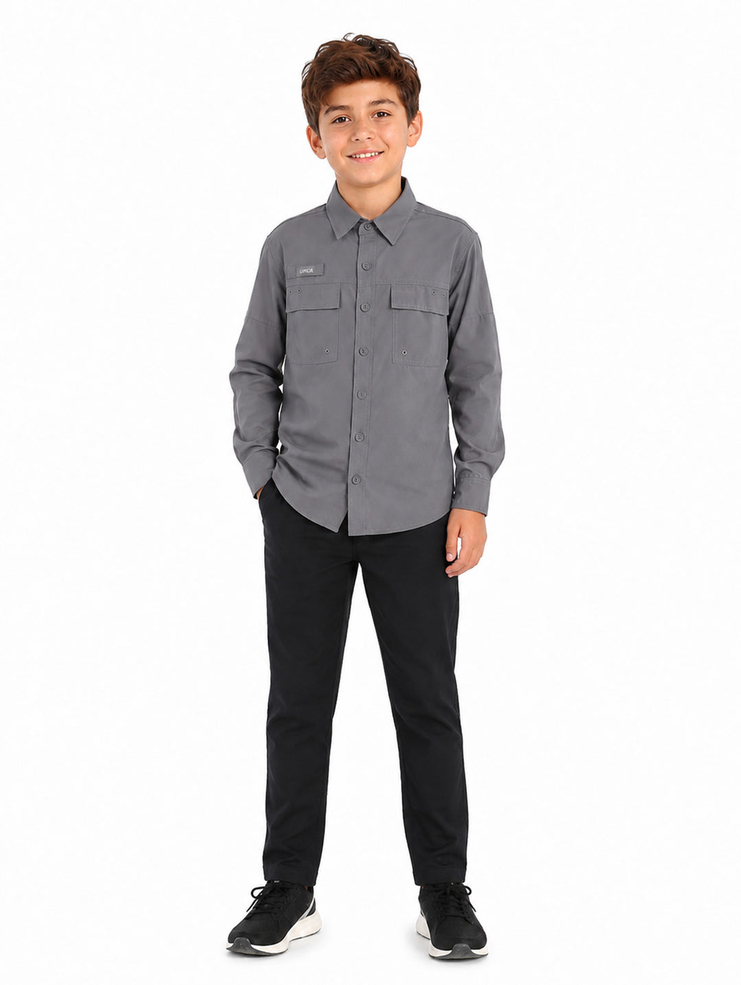 Niño vistiendo una camisa gris de manga larga con bolsillos frontales y cuello.