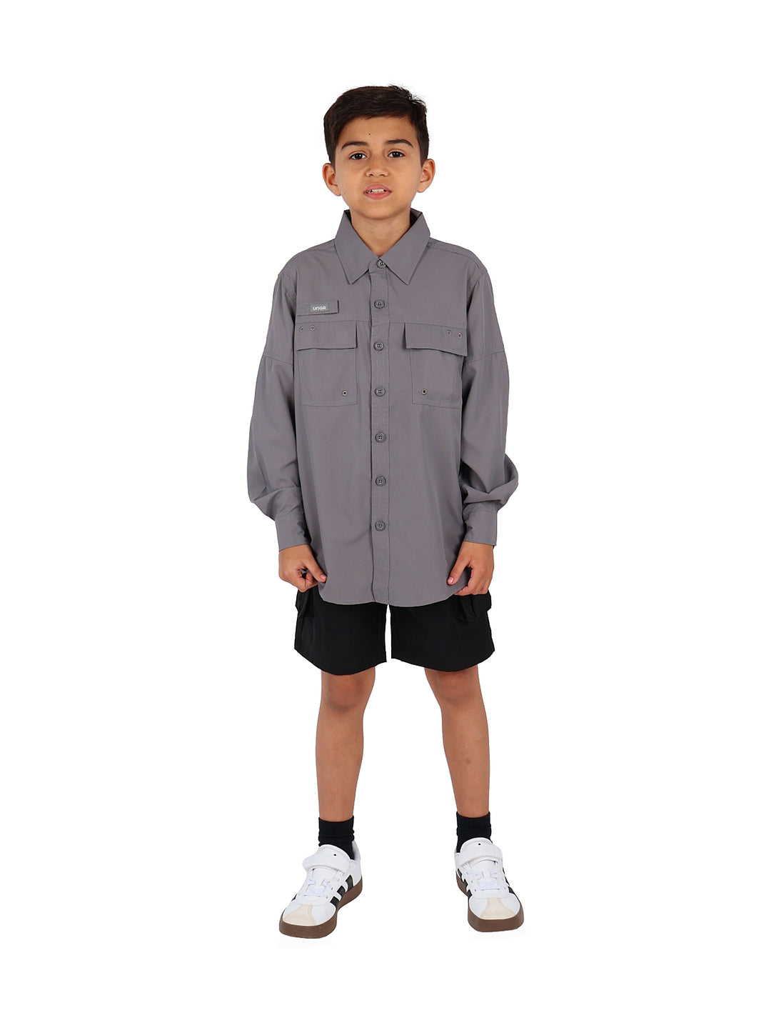 Niño vistiendo una camisa gris de manga larga con bolsillos frontales y cuello.