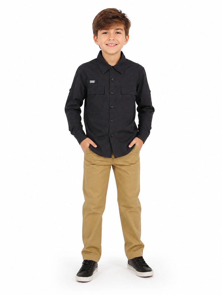 Niño vistiendo una camisa negra de manga larga estilo outdoor con botones y bolsillos frontales.