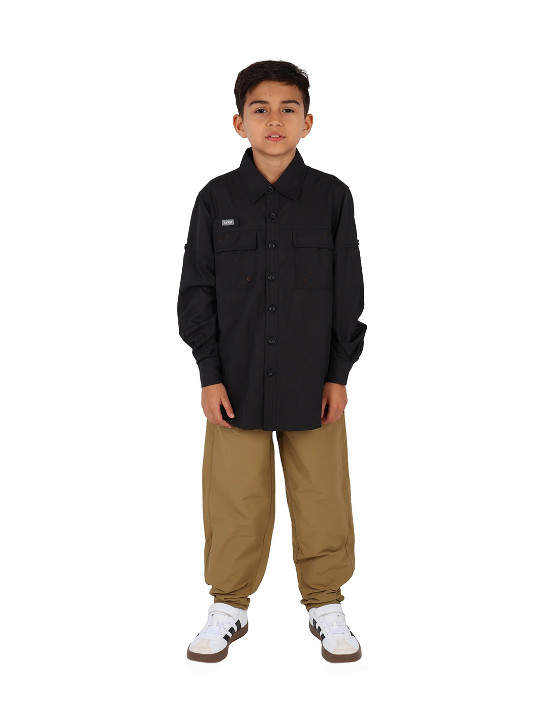Niño vistiendo una camisa negra de manga larga estilo outdoor con botones y bolsillos frontales.