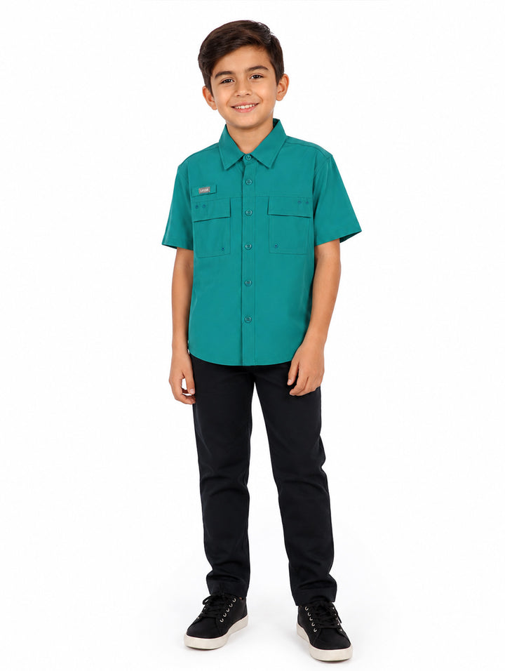 Niño vistiendo una camisa outdoor de color verde con manga corta y bolsillos frontales.