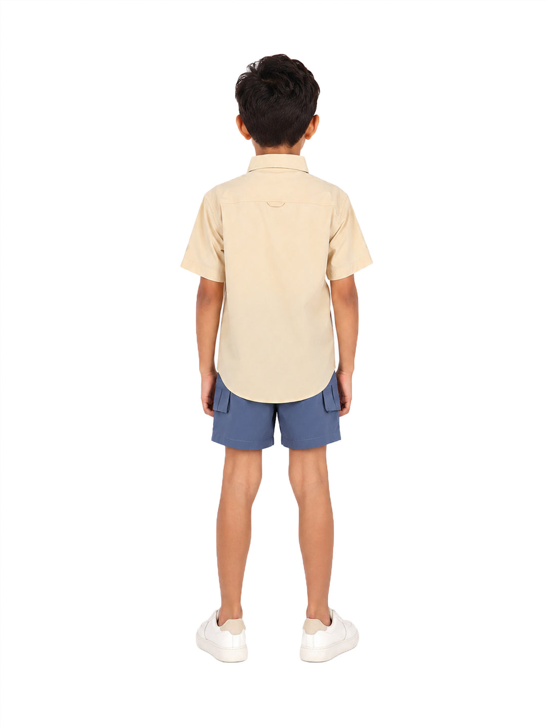 Niño vistiendo una camisa outdoor de manga corta color beige con bolsillos frontales.