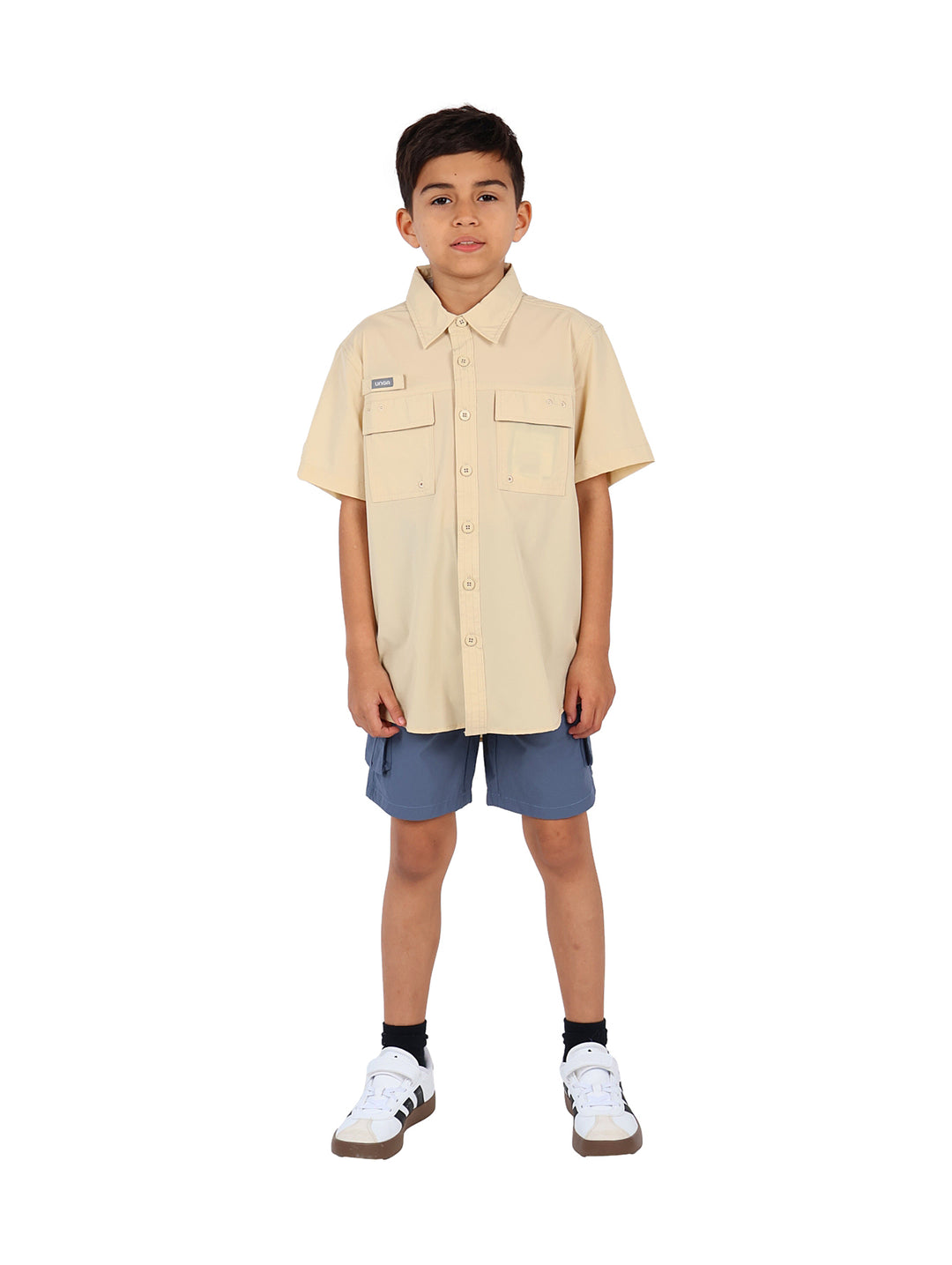 Niño vistiendo una camisa outdoor de manga corta color beige con bolsillos frontales.