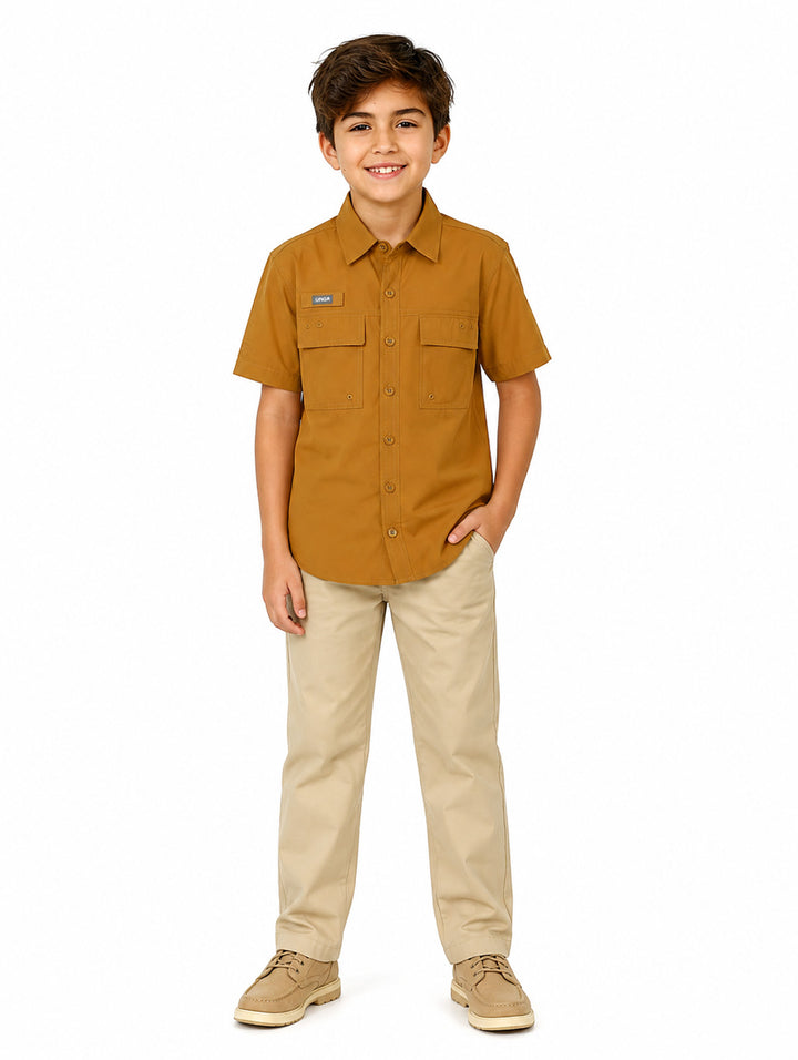 Niño vistiendo una camisa outdoor de manga corta color marrón con bolsillos frontales y botones.