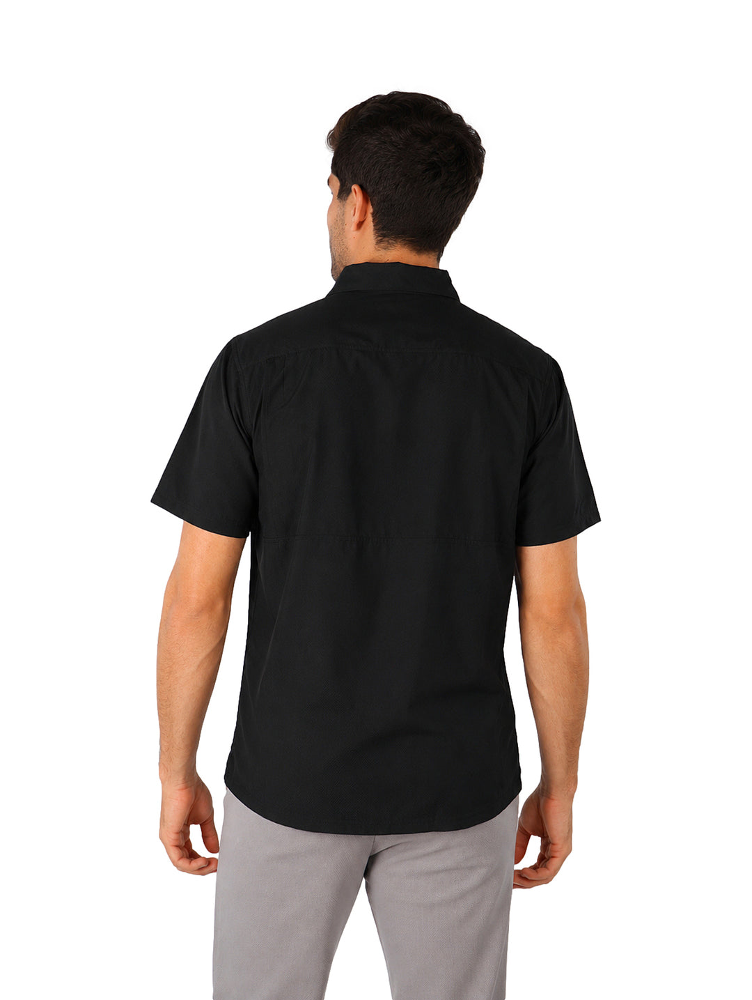 Hombre vistiendo una camisa outdoor de manga corta color negro, corte regular fit con botones y bolsillo frontal.