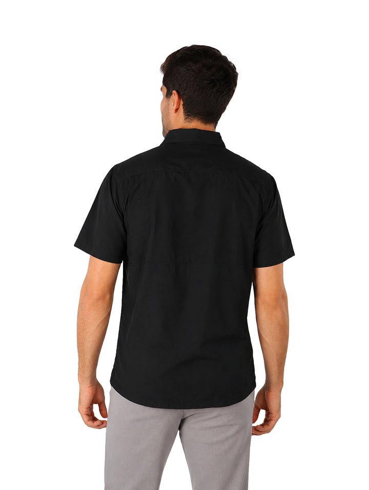 Hombre vistiendo una camisa outdoor de manga corta color negro, corte regular fit con botones y bolsillo frontal.