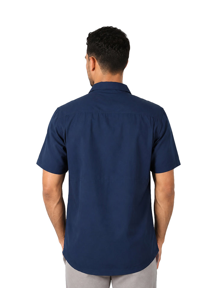 Hombre vistiendo una camisa outdoor de manga corta en color azul nocturno con cuello y botones.
