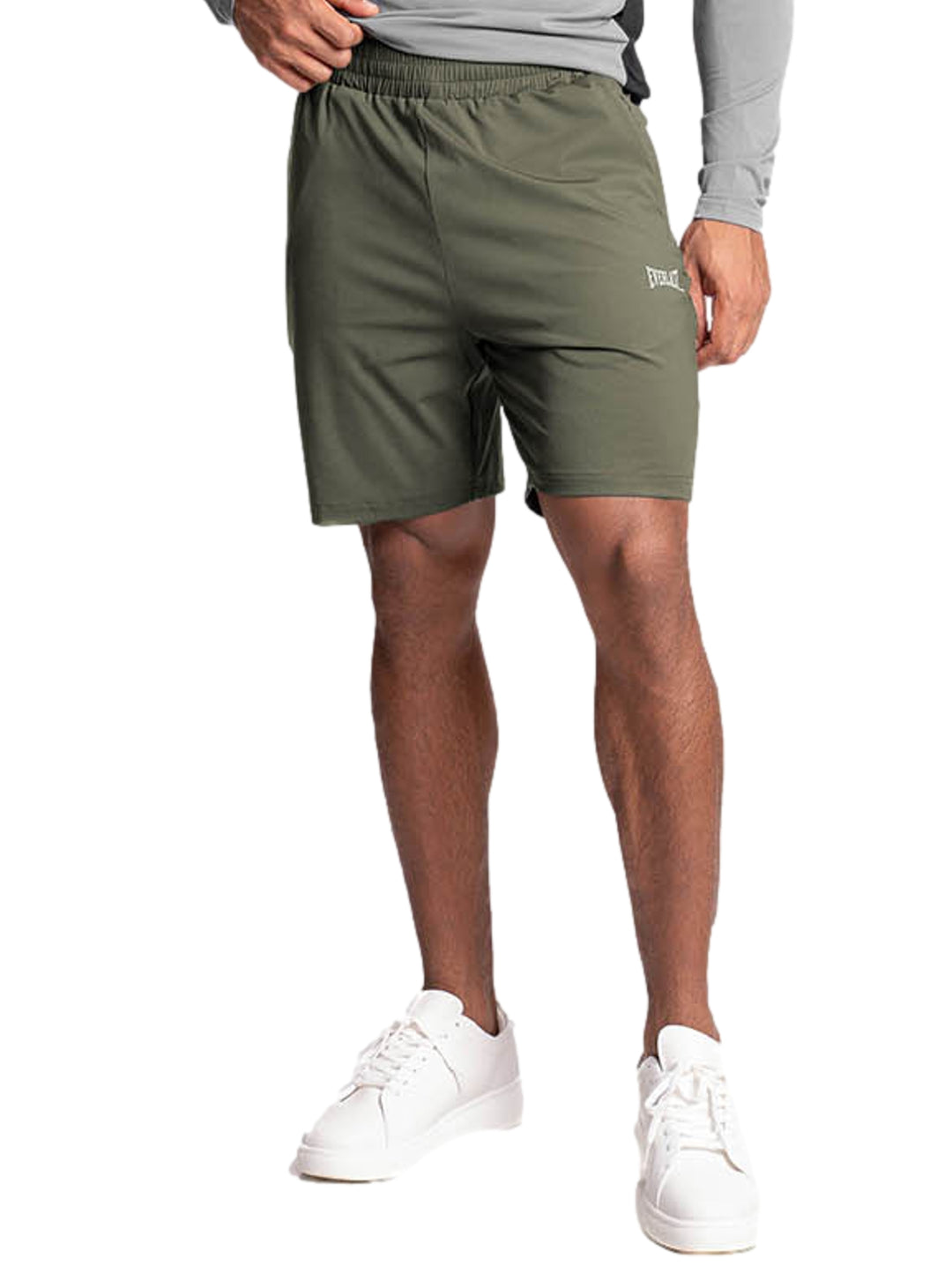 Hombre vistiendo un short deportivo de color olivo marca Everlast con tenis blancos.