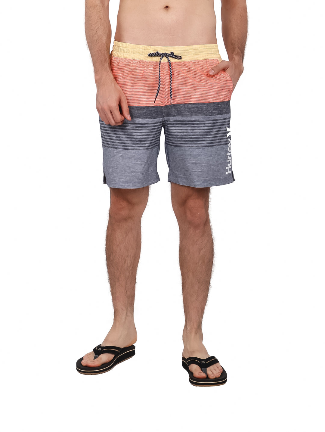 Hombre usando traje de baño Hurley color gris y naranja con rayas horizontales.