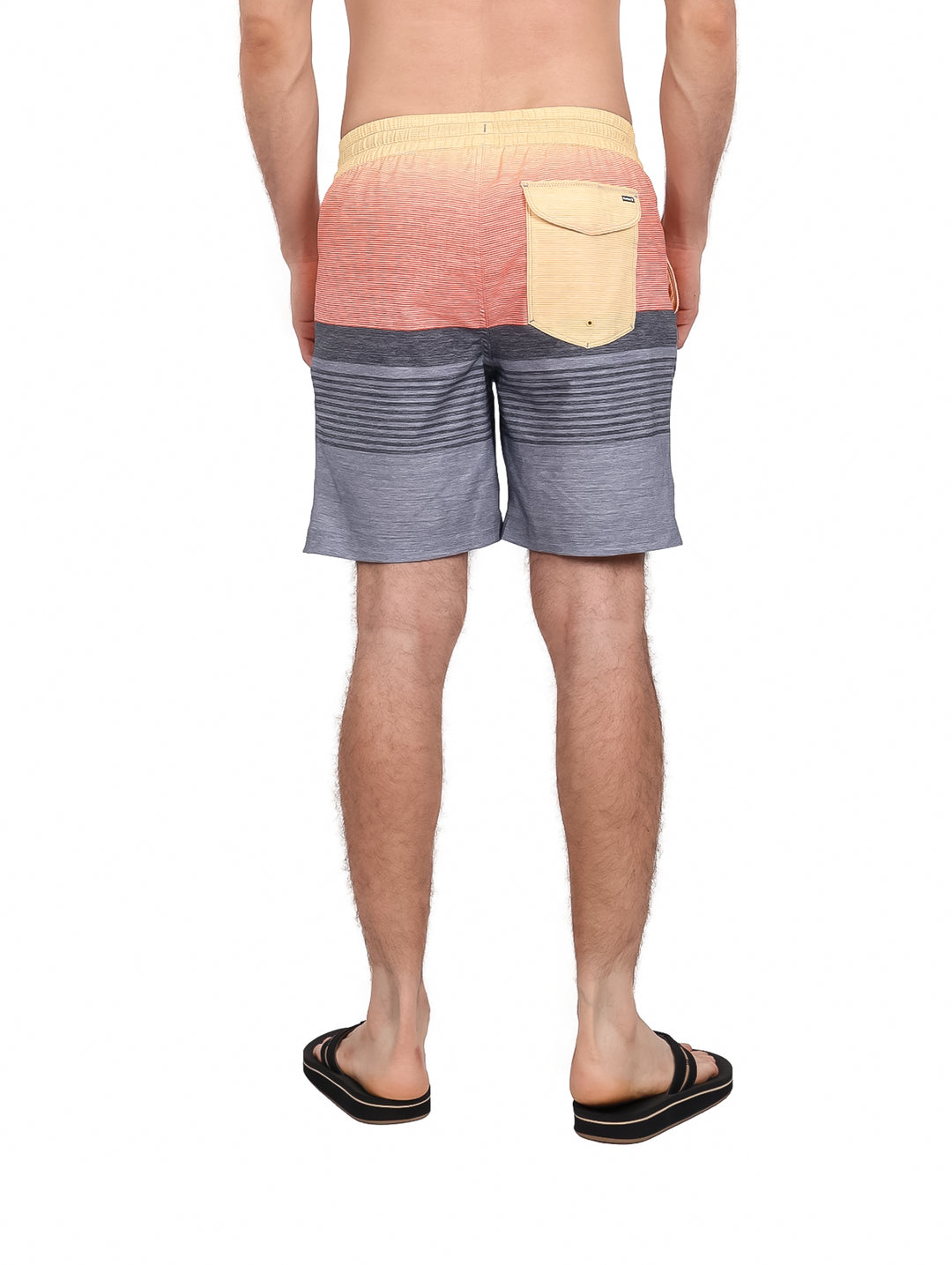Hombre usando traje de baño Hurley color gris y naranja con rayas horizontales.