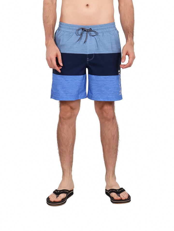 Hombre vistiendo traje de baño Hurley color azul mystic blue con diseño de franjas horizontales.