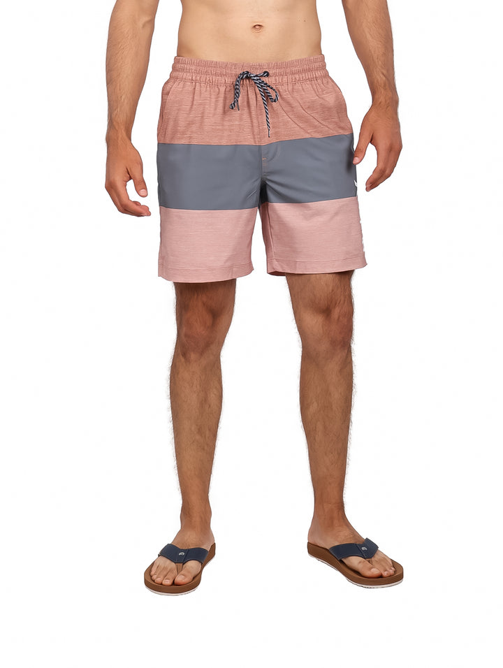 Hombre vistiendo traje de baño Hurley color auburn con franja gris y sandalias