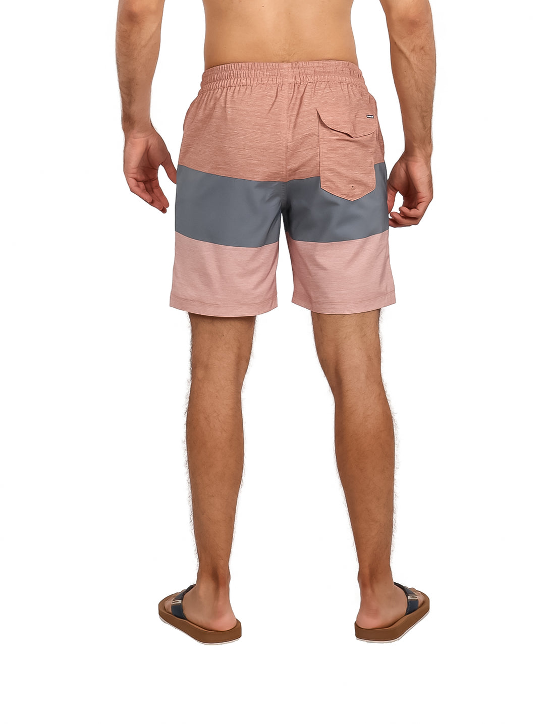 Hombre vistiendo traje de baño Hurley color auburn con franja gris y sandalias