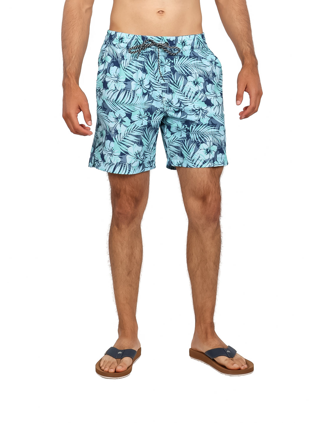 Hombre vistiendo traje de baño Hurley azul con estampado tropical de hojas.