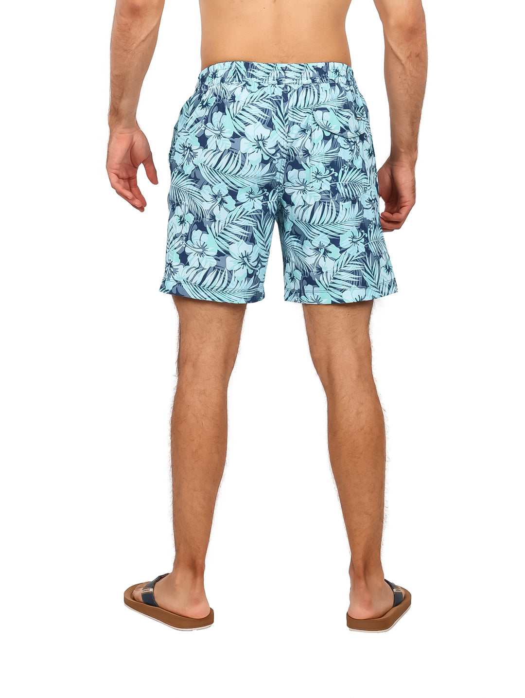 Hombre vistiendo traje de baño Hurley azul con estampado tropical de hojas.
