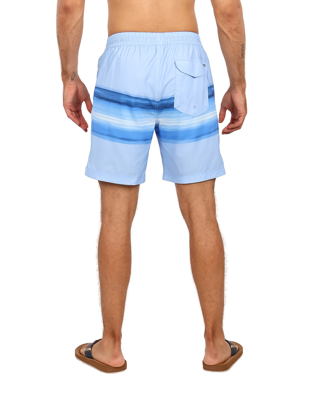 Hombre vistiendo traje de baño Hurley color azul místico con diseño de rayas horizontales.