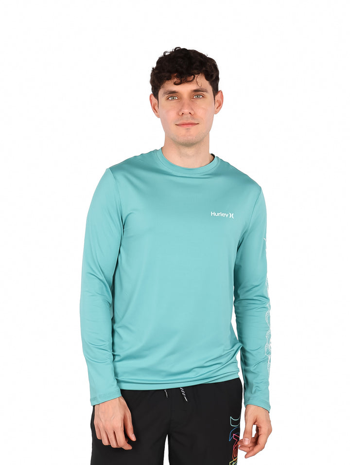 Hombre vistiendo playera de manga larga color verde jade de la marca Hurley.