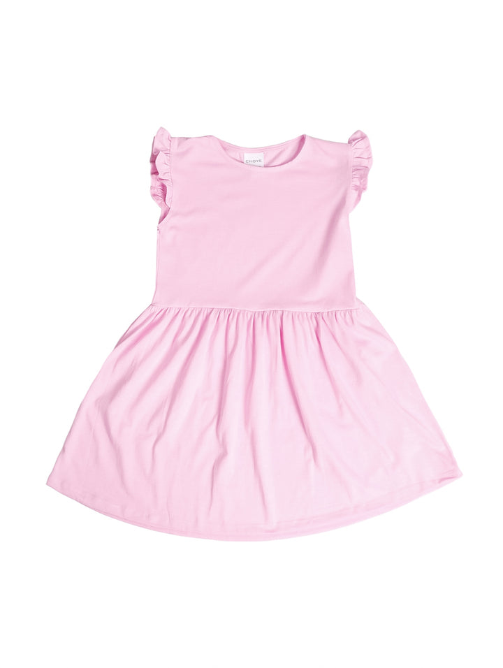 Niña vistiendo un vestido corto color rosa fiusha con detalles de volantes en los hombros y calzado blanco.