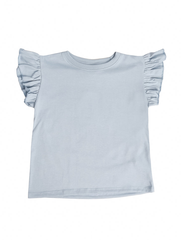 Niña vistiendo una camiseta azul claro con mangas volantes y shorts de mezclilla sobre fondo blanco.