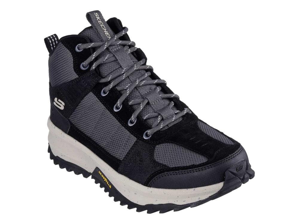 Bota deportiva Skechers en color negro y gris con suela blanca gruesa y tracción para actividades al aire libre.