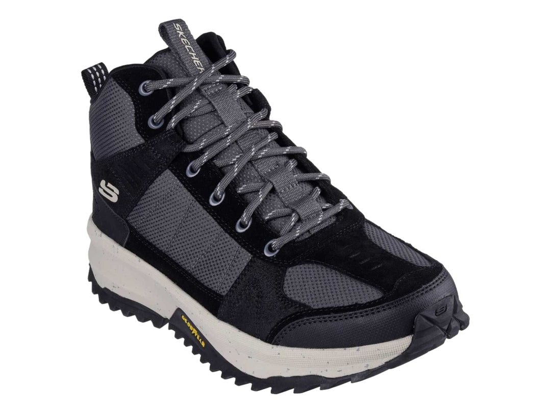 Bota deportiva Skechers en color negro y gris con suela blanca gruesa y tracción para actividades al aire libre.