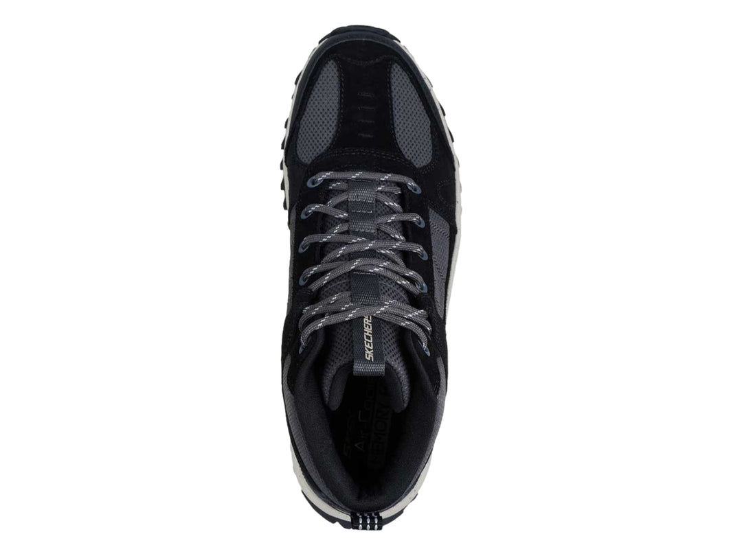 Bota deportiva Skechers en color negro y gris con suela blanca gruesa y tracción para actividades al aire libre.
