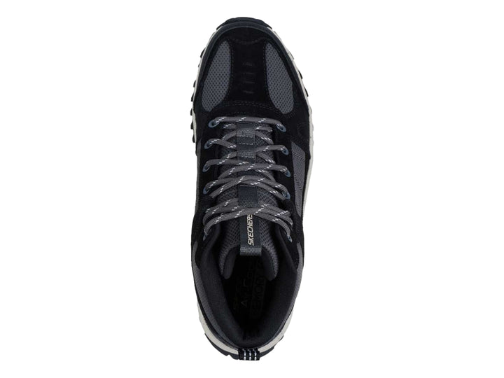 Bota deportiva Skechers en color negro y gris con suela blanca gruesa y tracción para actividades al aire libre.